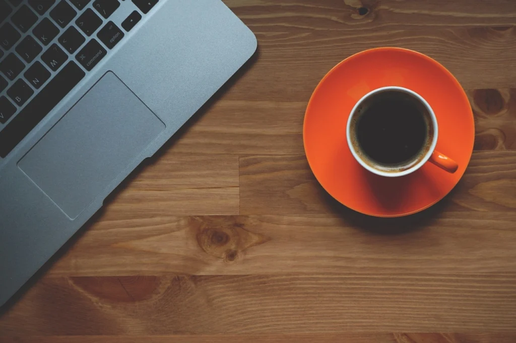 Laptop with email inbox open on screen and coffee cup on desk